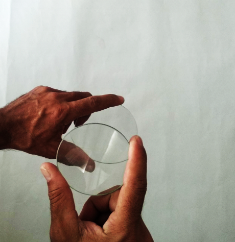 Foto das mãos segurando as lentes uma a frente da outra conforme indicado no texto